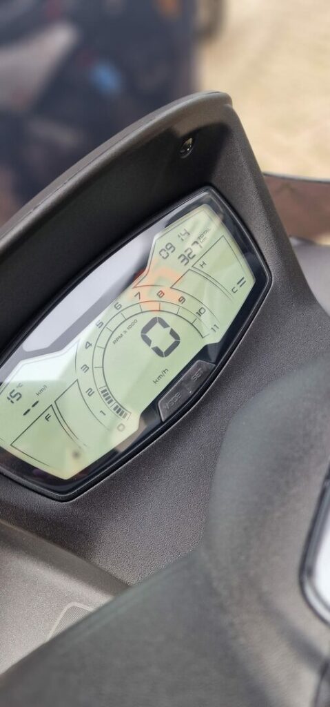 Close-up van een digitaal scooterdashboard met snelheidsmeter, toerenteller en brandstofniveau.