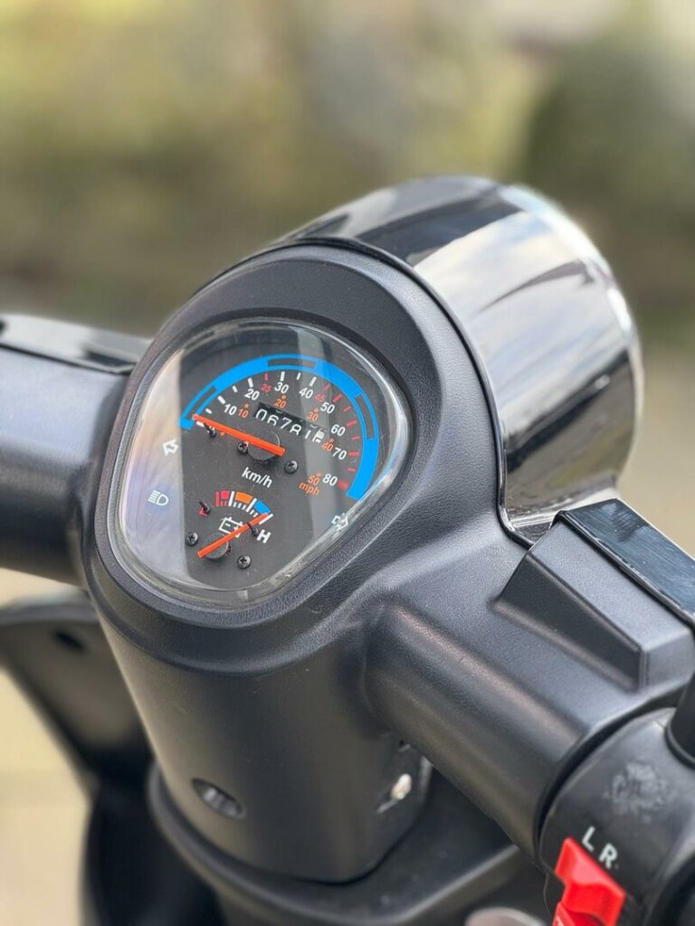 Close-up van het dashboard van een scooter met snelheidsmeter en brandstofmeter.