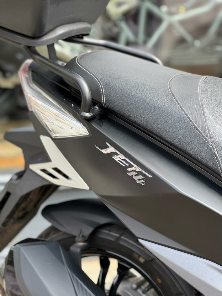 Close-up van de zijkant van een zwarte scooter met zadel, grijphandvat en JET14-logo.