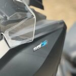 Close-up van een motorscooter met windscherm en Euro 5 Clean Power-sticker op matte kuip.