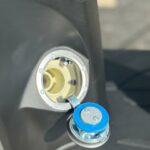 Open brandstofdop van een scooter, met blauwe dop op scharnier, close-up