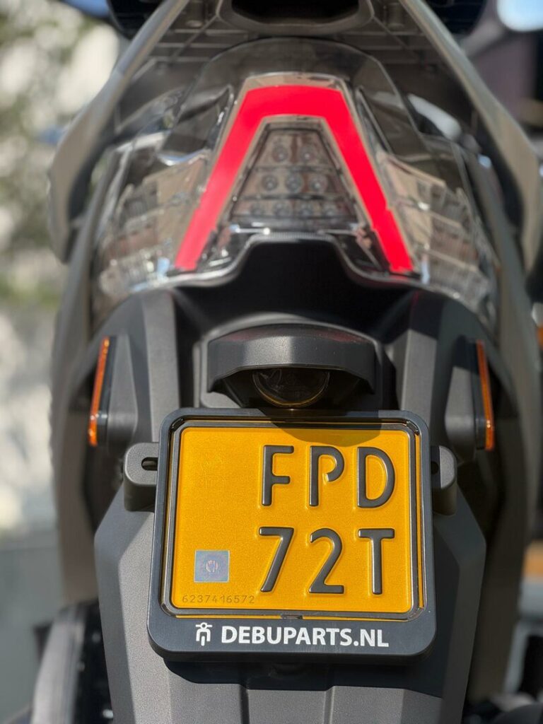 Achterkant van een motorfiets met gele NL kentekenplaat, LED-achterlicht en kentekenplaathouder DEBUPARTS.NL