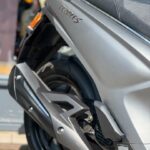 Close-up van de achterzijde van een zilveren scooter met People S-logo, uitlaat en zadel in beeld.