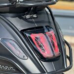 Close-up van het achterlicht en de bagagedrager van een matte zwarte scooter.