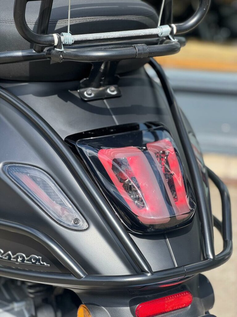 Close-up van het achterlicht en de bagagedrager van een matte zwarte scooter.