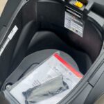 Opbergruimte onder het zadel van een scooter met handleiding en gereedschapsset.