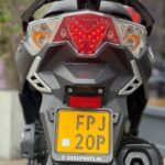 Achterkant van een scooter met brandend led-achterlicht en gele Nederlandse kentekenplaat.