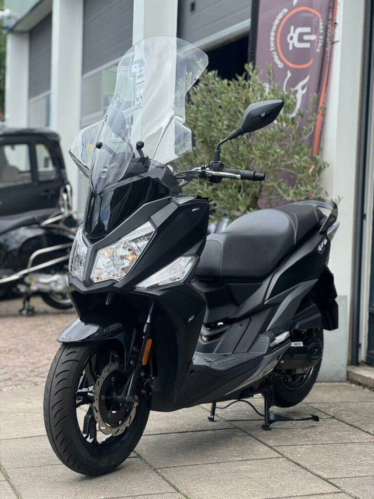 Zwarte maxi-scooter met hoog windscherm op standaard voor een werkplaats