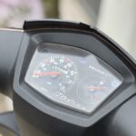 Close-up van het dashboard van een Peugeot Kisbee scooter met snelheidsmeter en brandstofmeter.