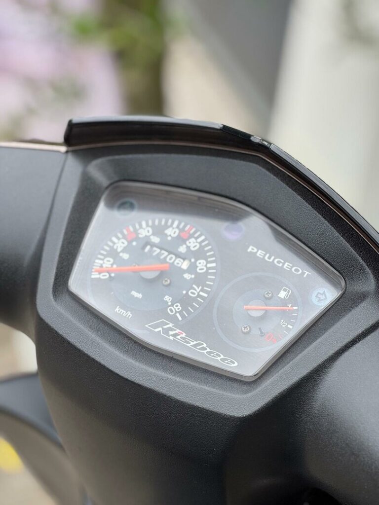 Close-up van het dashboard van een Peugeot Kisbee scooter met snelheidsmeter en brandstofmeter.