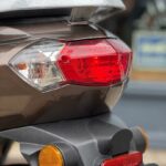 Achterkant van scooter met rood achterlicht, knipperlichten en bagagedrager.