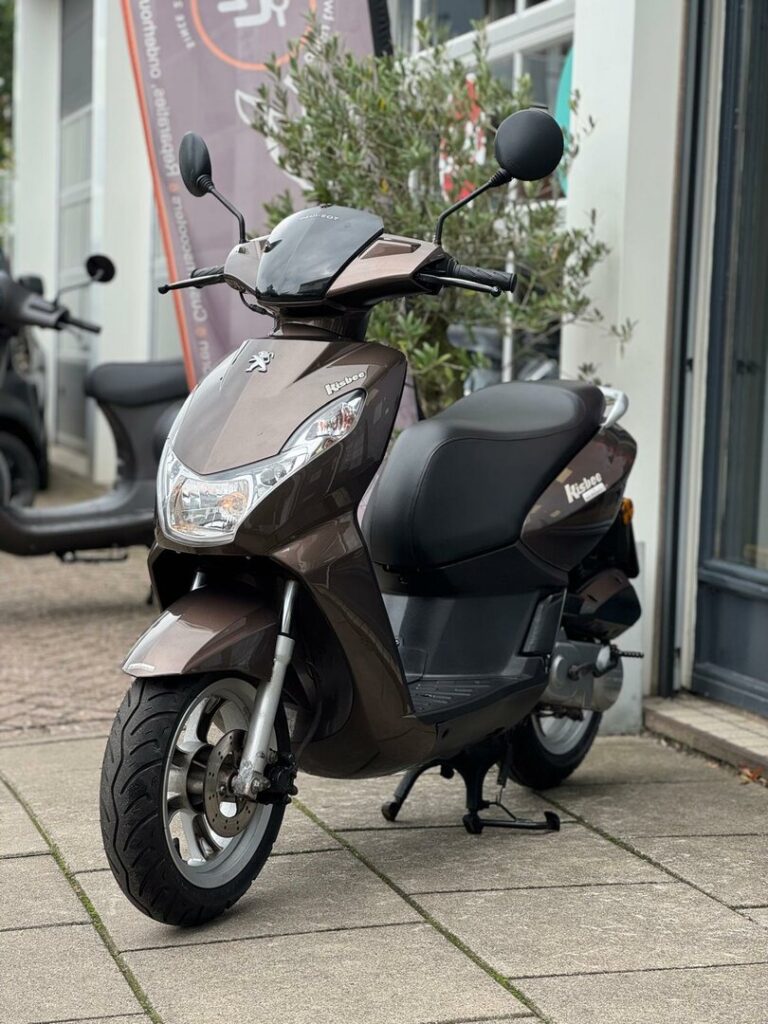 Bruine Peugeot Kisbee scooter geparkeerd op standaard voor een winkelpui.