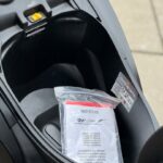 Opbergruimte onder het zadel van een scooter met handleiding in plastic zak