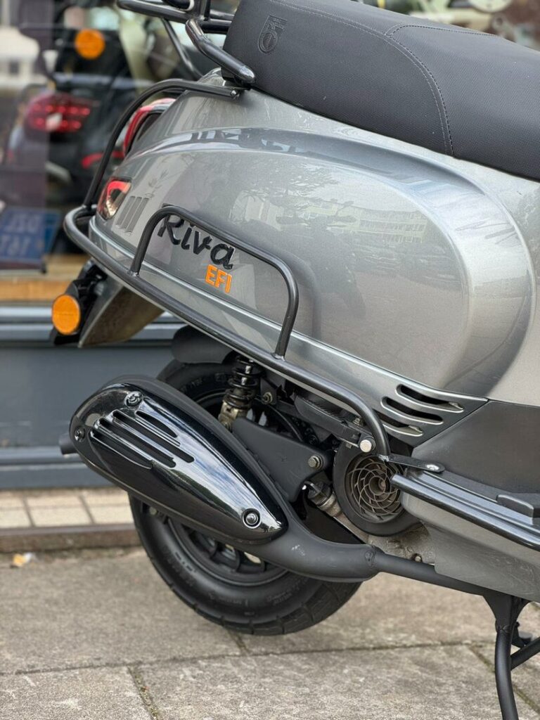 Close-up van de achterzijde van een grijze Riva EFI scooter met uitlaat, wiel en bagagedrager.