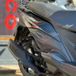 Close-up van de achterkant van een zwarte scooter met uitlaat, achterwiel en zadel.