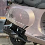 Close-up van de achterzijde van een metallic roze AGM VX50S scooter met uitlaat en zadel.