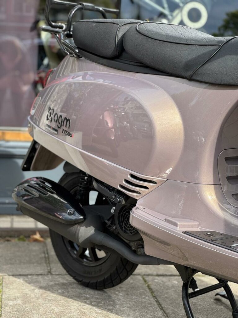 Close-up van de achterzijde van een metallic roze AGM VX50S scooter met uitlaat en zadel.