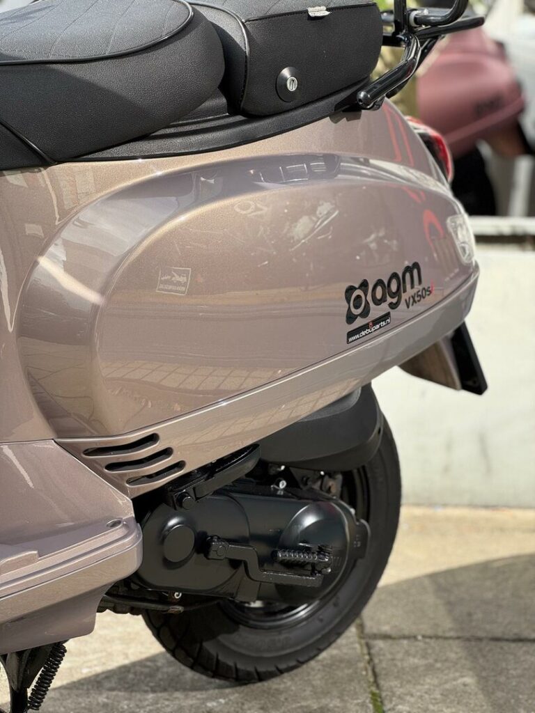 Close-up van de achterzijde van een beige AGM VX50S-scooter met zadel, motor en achterwiel.