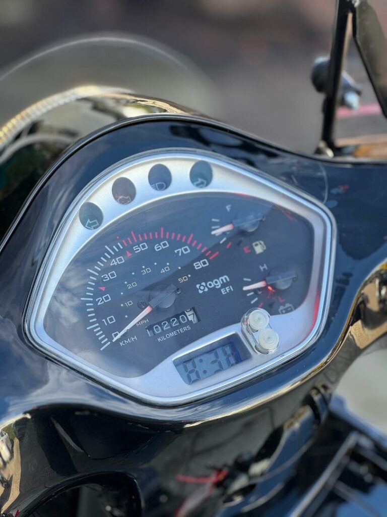 Close-up van een scooterinstrumentenpaneel met snelheidsmeter, kilometerteller en digitale klok