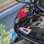 Close-up van de achterkant van een zwarte scooter met bagagerek, achterlicht en blauw kenteken.