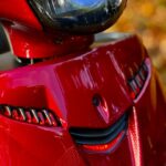 Close-up van de voorkant van een rode scooter met koplamp en rode LED-details.
