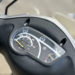 Close-up van het dashboard van een scooter met snelheidsmeter en benzinemeter.