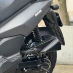 Close-up van de achterzijde van een zwarte scooter met veer en achterwiel.