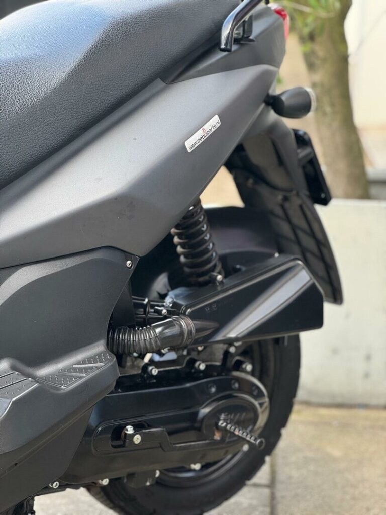 Close-up van de achterzijde van een zwarte scooter met veer en achterwiel.