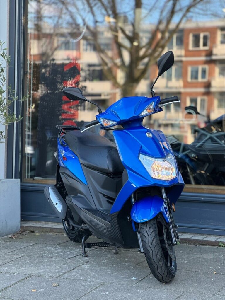 Blauwe scooter op standaard geparkeerd voor een winkelraam in de stad