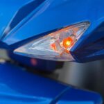 Close-up van een brandende oranje richtingaanwijzer op blauwe scooter met Euro4-sticker