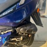 Close-up van de achterzijde van een blauwe G-Dink scooter met uitlaat en wiel.