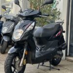 Zwarte SYM-scooter op standaard voor een showroom, schuin van voren gefotografeerd.