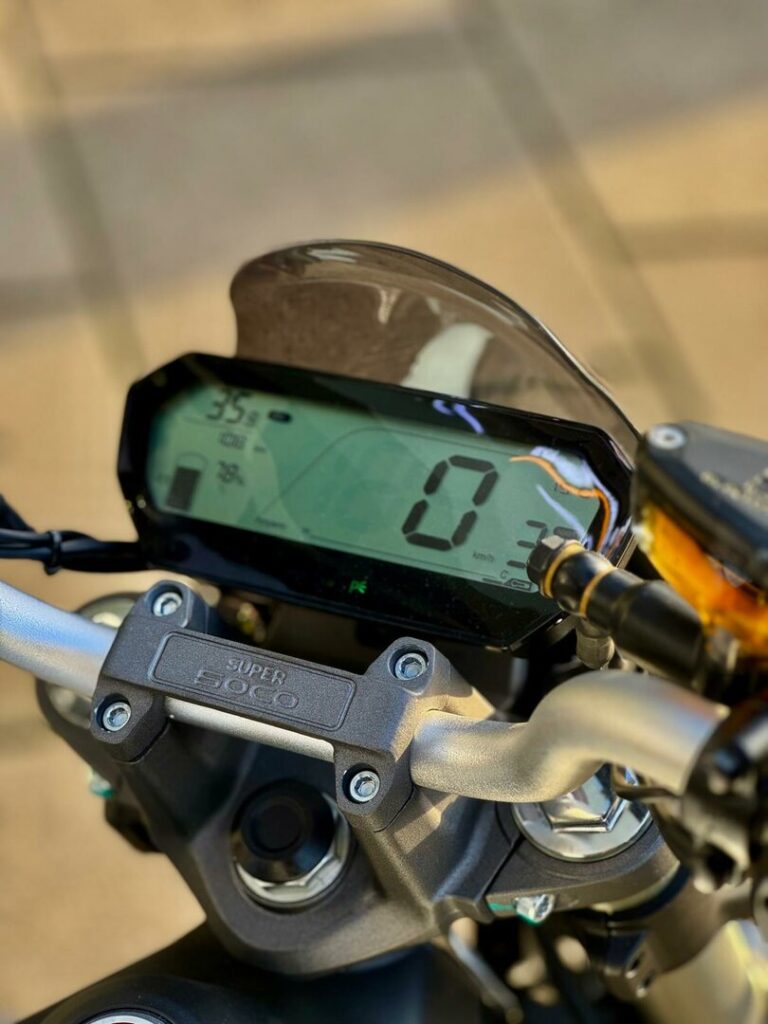 Close-up van een motorstuur met digitaal dashboard van Super Soco, snelheid 0 km/u zichtbaar.