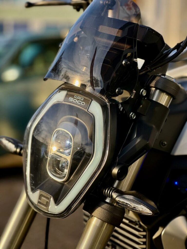 Close-up van de koplamp en het windscherm van een Super Soco elektrische motorfiets.
