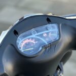 Close-up van een scooterdashboard met snelheidsmeter en gescheurde, vervormde kunststof kap.