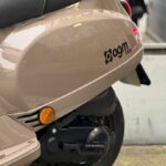 Close-up van de achterzijde van een beige AGM VX50-scooter met zadel, richtingaanwijzer en achterwiel.