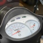 Close-up van het dashboard van een SYM scooter met snelheidsmeter en brandstofmeter.