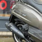 Close-up van de achterzijde van een grijze scooter met uitlaat, zadel en Fiddle III 50S-logo.