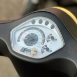 Close-up van het dashboard van een scooter met snelheidsmeter en brandstofmeter.