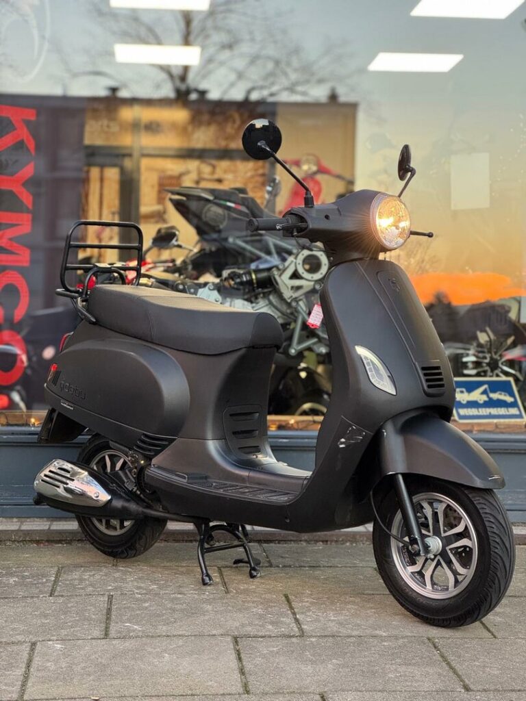 Matzwarte retro-scooter op de standaard voor een showroom, met brandende koplamp.