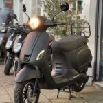 Matzwarte scooter met brandende koplamp op standaard voor een winkel