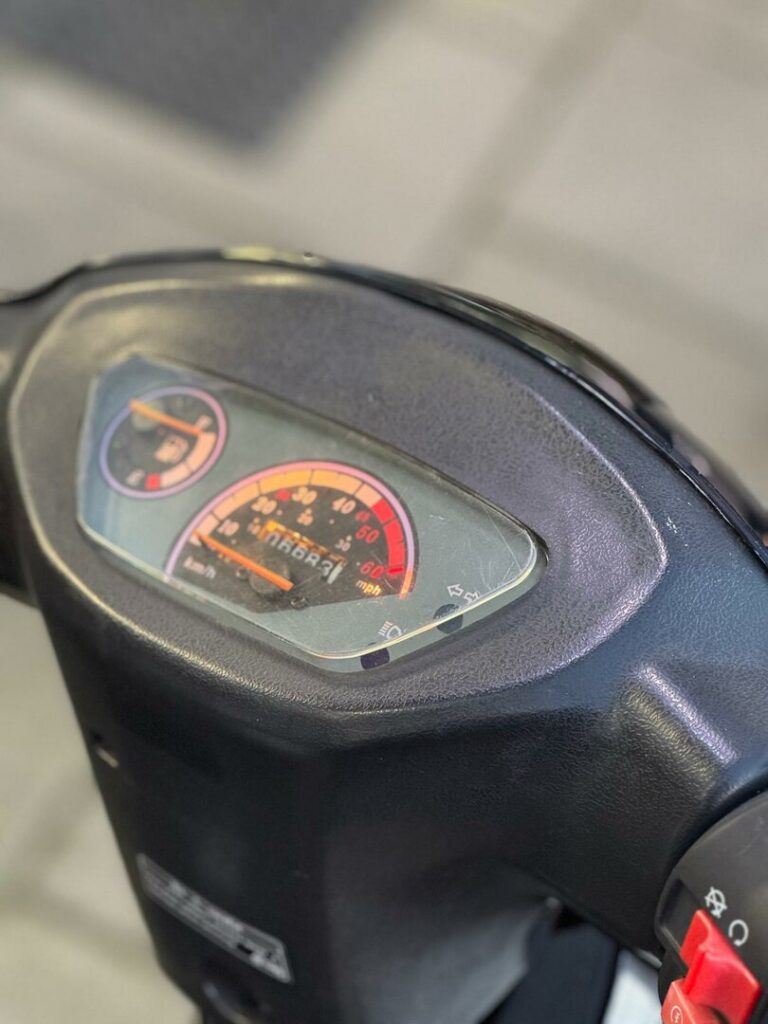 Close-up van het dashboard van een scooter met snelheidsmeter en brandstofmeter.