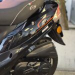 Detail van zwarte 50cc scooter met JET-logo, zadel en achterwiel, geparkeerd op straat.