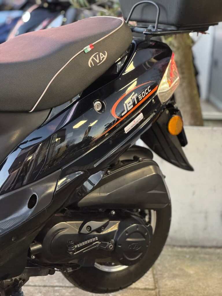 Detail van zwarte 50cc scooter met JET-logo, zadel en achterwiel, geparkeerd op straat.