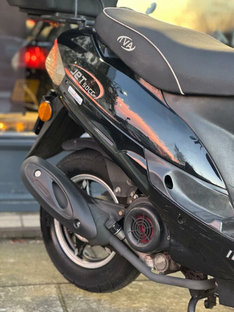 Close-up van de achterzijde van een zwarte 50cc-scooter met uitlaat, achterwiel en zadel.