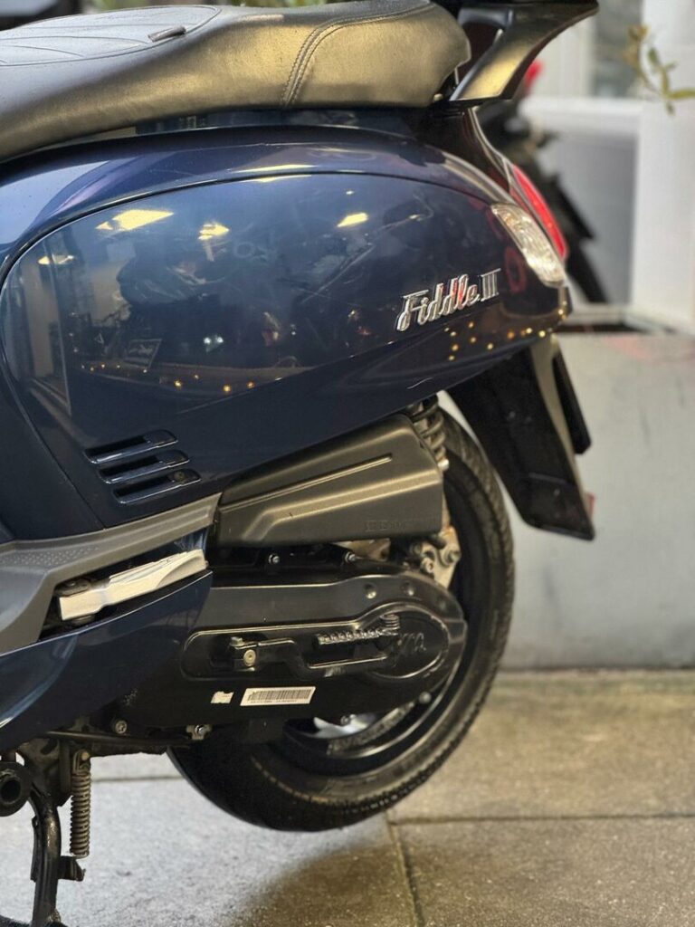 Close-up van de achterzijde van een donkerblauwe Fiddle III scooter op standaard.