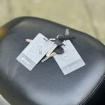 Sleutels met twee Segway-kaarten liggen op een zwart scooterzadel buiten.