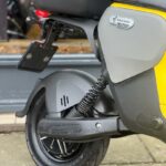 Close-up van het achterwiel en de vering van een gele Segway B110S e-scooter.