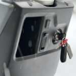 Close-up van scooterdashboard met contactslot, sleutelbos, USB-poort en opbergvak.