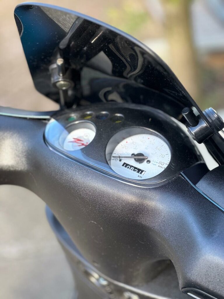 Close-up van het dashboard van een scooter met snelheidsmeter en kilometerteller.